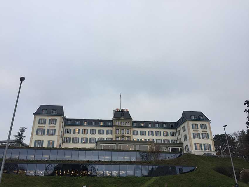 The International Committee of the Red Cross's headquarters are in a large old building which says 'CICR' in big letters on the roof. In the hills in front of the historic building, a large window front can be seen, seemingly of more modern architecture.